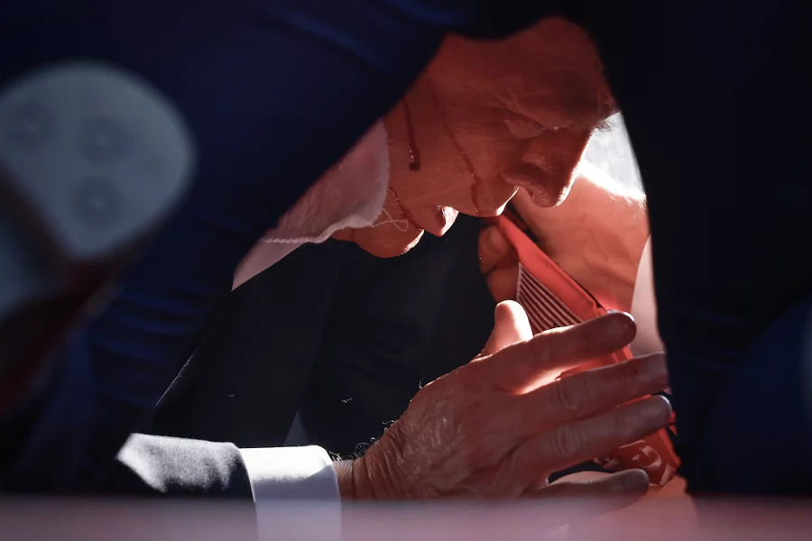 Former President Trump is shown covered by U.S. Secret Service agents after an incident.